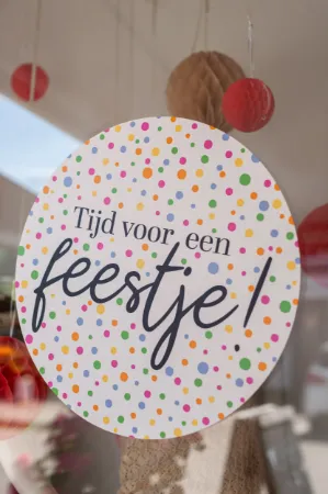 Ronde witte raamsticker met feestelijke confetti en de tekst 'Tijd voor een feestje'
