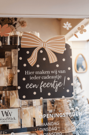 Raamsticker met vrolijke tekst over feestelijke cadeaus, ideaal voor winkels.